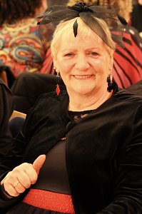 Karnevalsspektakel in einem gro&szlig;en Raum. Viele bunt gekleidete Menschen an Tischen und auf der B&uuml;hne