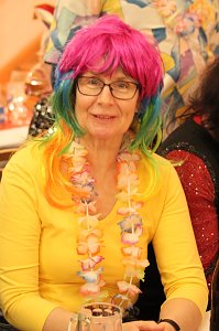 Karnevalsspektakel in einem gro&szlig;en Raum. Viele bunt gekleidete Menschen an Tischen und auf der B&uuml;hne