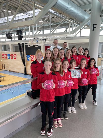 Tobias Ernst (stellv. Vorsitzender des Vereins) (h.r.) und Andrej Minewski (Trainer der D-Jugend) (h.l.) zusammen mit den M&auml;dchen der D- und E-Jugend des THC bei der symbolischen Scheck&uuml;bergabe (Foto: Landratsamt UHK)