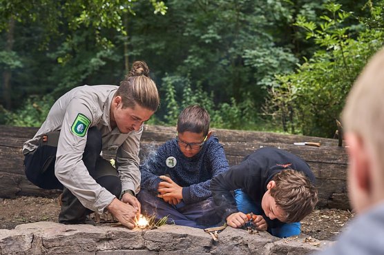 Vier Tage und drei N&auml;chte sind die Kinder in der Natur des Nationalparks Hainich unterwegs. Im Hintergrund ist eine Schlafstelle zu sehen. Foto: Tino Sieland Hier lernen die Kinder vom Ranger, mit dem Feuerstahl ein Feuer zu entfachen. (Foto: Tino Sieland)