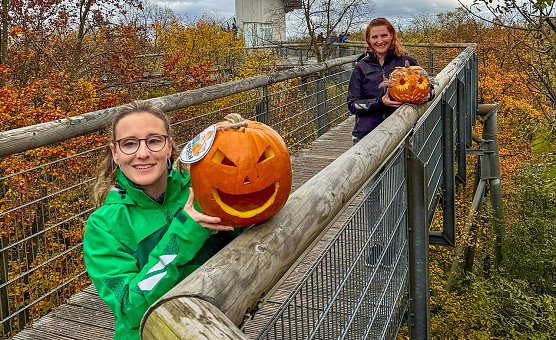 Sandy-Ann Bergmann und Diana Ludwig (v.l.n.r.) vom Team des Baumkronen- pfades pr&auml;sentieren zwei schaurig sch&ouml;ne K&uuml;rbisgesichter.  (Foto: KTL Kur und Tourismus Bad Langensalza GmbH)