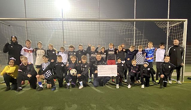 Bild: Toni Hyseni (vorne in der Mitte mit Scheck) &uuml;berreicht den Fu&szlig;ballern 1.000 Euro