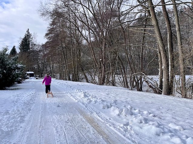 Bild: Ein M&auml;dchen zieht einen Schlitten durch eine schneeverscheite Landschaft. 