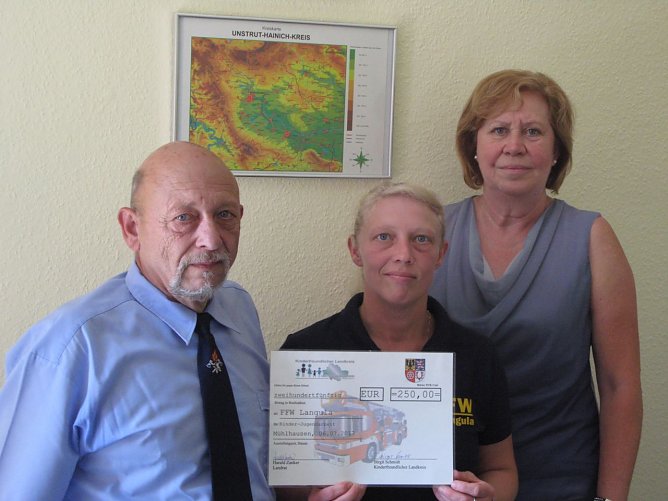 Zur Unterst&uuml;tzung der Kinder- und Jugendarbeit in der Wehr erhielten heute der Brandmeister und Vereinsvorsitzenden J&ouml;rg Rollberg und die Jugendwartin Diana Sch&uuml;tz von Landrat Harald Zanker einen symbolischen Scheck vom Kinderfreundlichen Landkreis in H&ouml;he von 250,00 Euro.  (Foto: Pressestelle Landratsamt Unstrut-Hainich-Kreis)