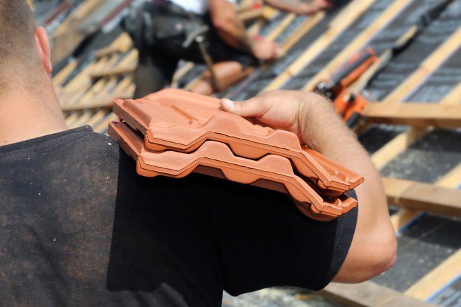 Geschulterte Pfannen auf dem Dach (Foto: IG BAU)