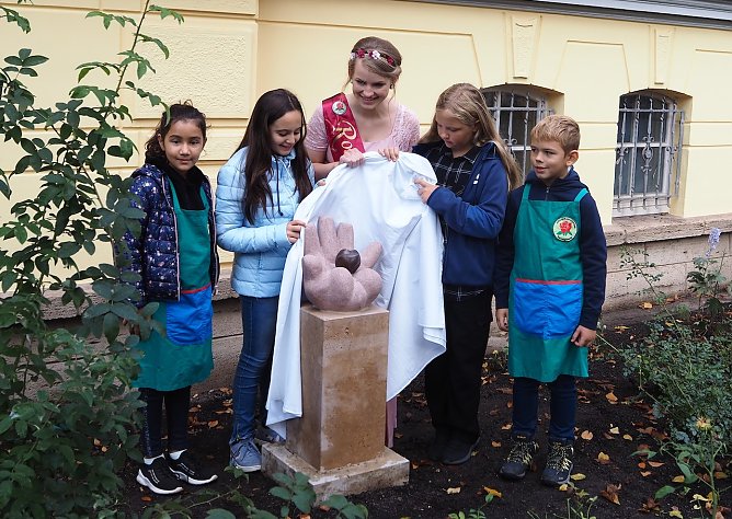 Die Rosenk&ouml;nigin enth&uuml;llt mit den Kindern die neue Skulptur in ihrem Rosengarten (Foto: Anni-Berger-Stiftung)