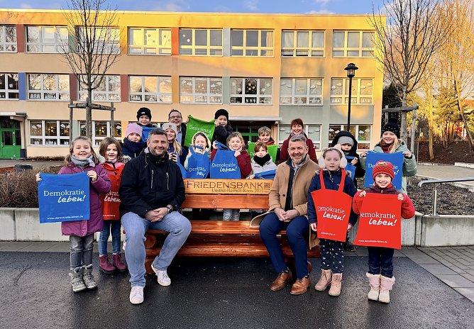 Der Landrat des Unstrut-Hainich-Kreises, Thomas Ahke (Bank rechts), wurde zur offiziellen &Uuml;bergabe der Friedensbank herzlich von den Sch&uuml;lerinnen, Sch&uuml;lern und Schuldirektor Manuel Mettke (Bank links) empfangen. (Foto: Ronja Rothe)