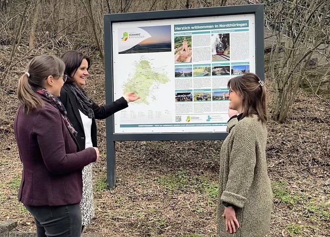 Fr. Mucke (Tourismusverband S&uuml;dharz Kyffh&auml;user) und Fr. Suberg (Regionalmanagement) pr&auml;sentieren Landr&auml;tin Antje Hochwind-Schneider (mitte) die Touristische Hinweistafel in der Lohstra&szlig;e (Foto: Carina Ei&szlig;ner)