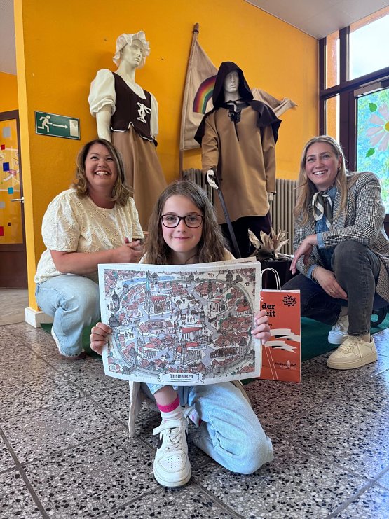 Bild: v. l.: Anke Wandt (Schulleiterin der Nikolaischule M&uuml;hlhausen), Frieda Pohl (8), Melanie Kura (Stadtmarketing)